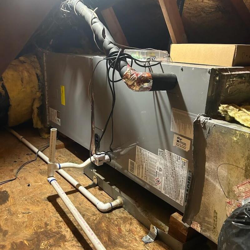 Air handler unit in attic with connected ductwork and piping