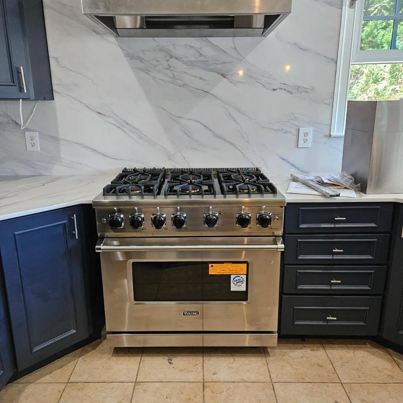 Viking gas range installed in kitchen with marble wall