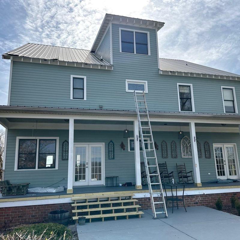 Metal roof inspection with ladder on residential house