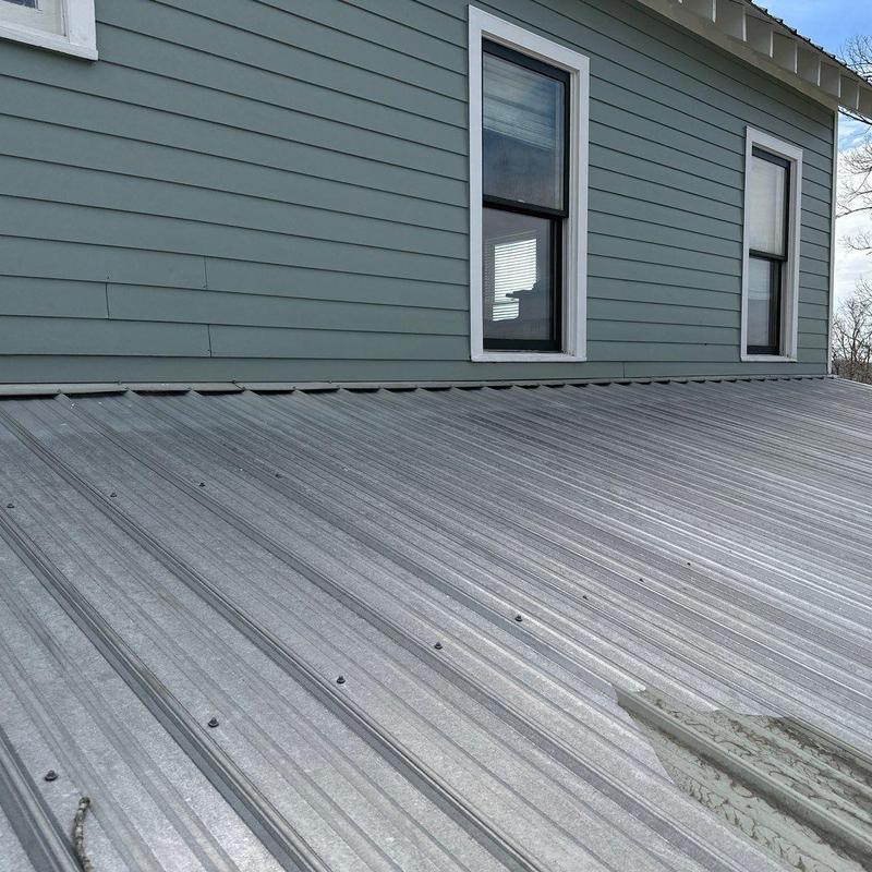 Metal roof panels with dent and damage near house siding