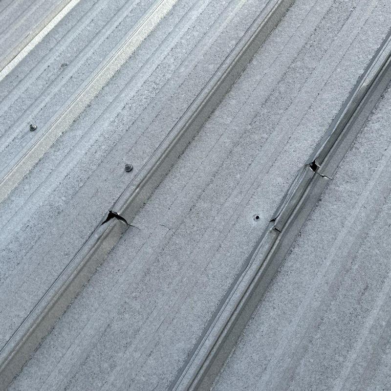 Metal roofing panels with visible cracks and damage