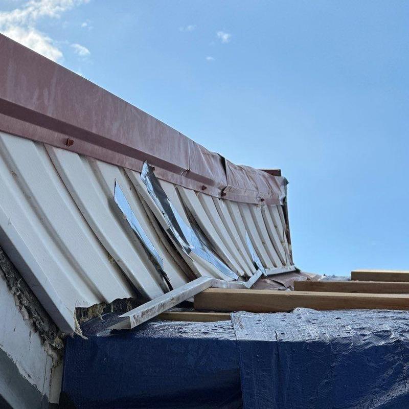 Metal roof panels damaged and bent after storm