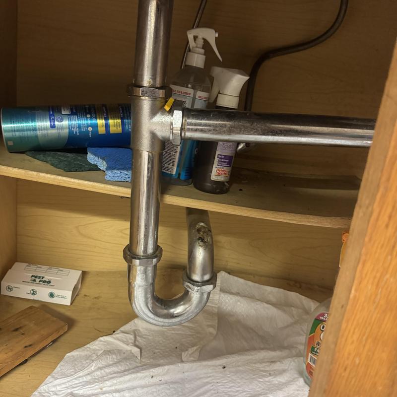 Kitchen sink drain pipes under cabinet with supplies