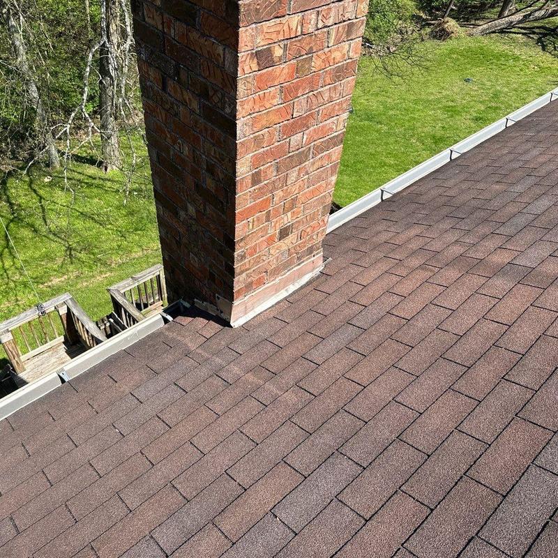 Roof shingles and flashing around brick chimney inspection