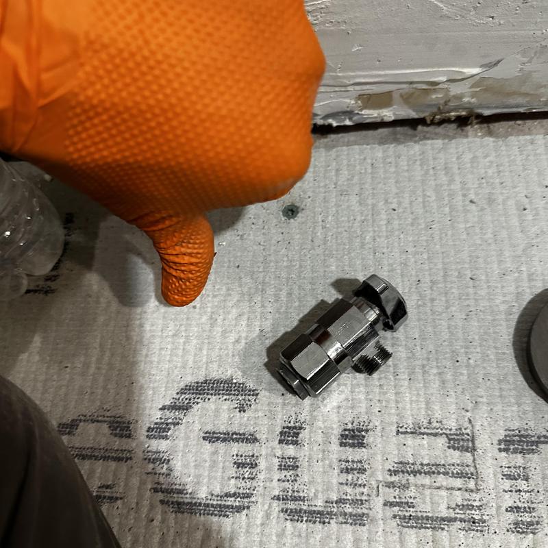 SharkBite angle stop valve on floor near glove