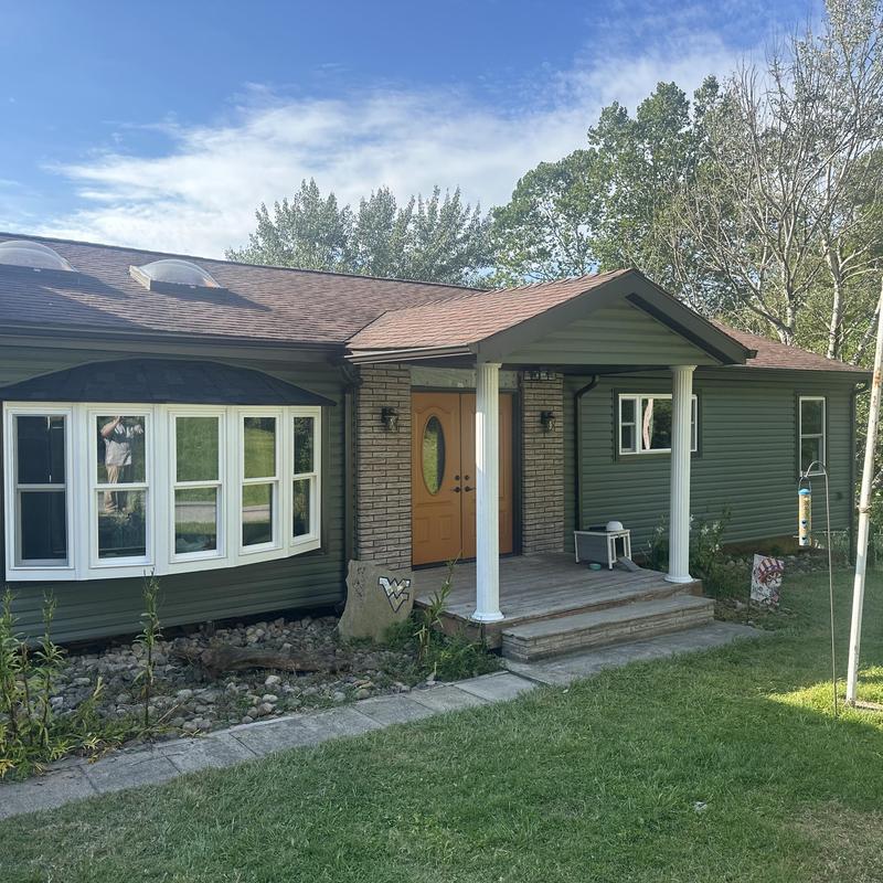 Bay window installation on green siding house exterior