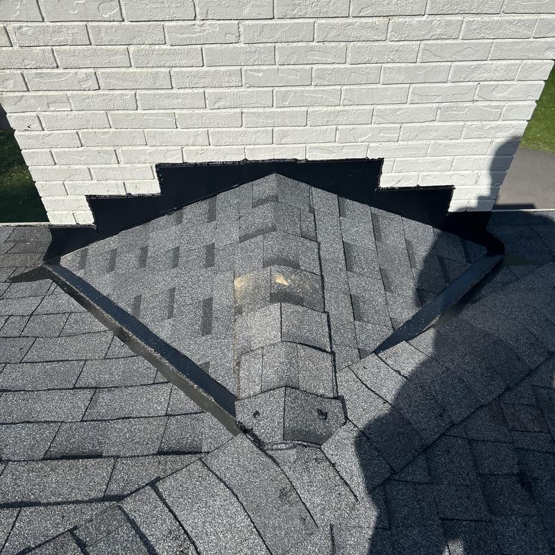 Chimney cricket with new asphalt shingles and flashing