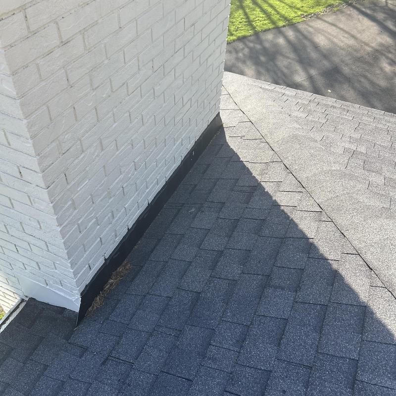 Chimney flashing and asphalt shingles on roof corner