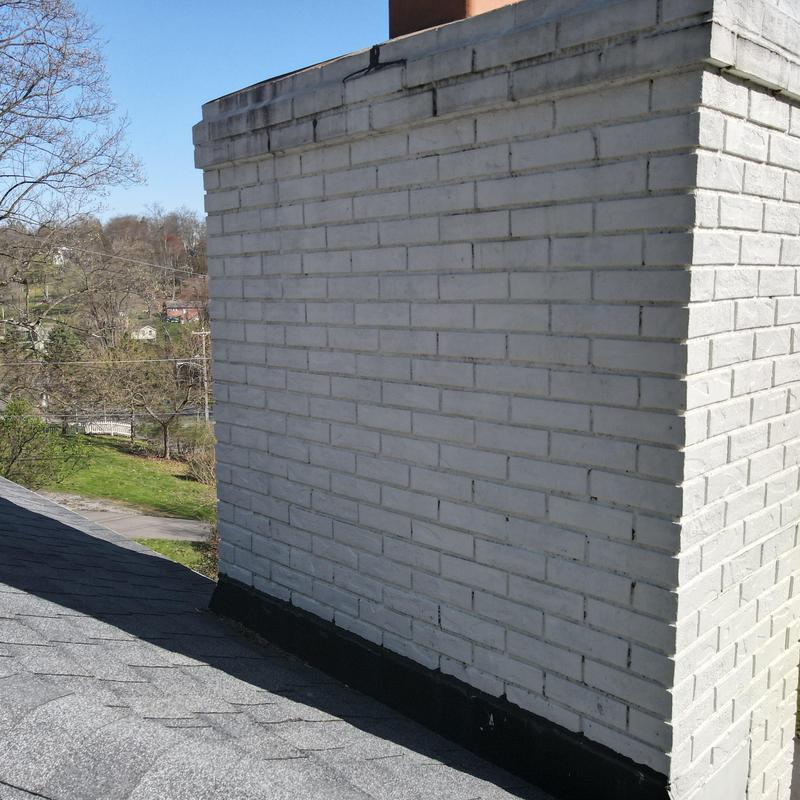 Chimney flashing and cricket installation on asphalt roof