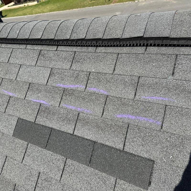Asphalt roof shingles with marked cracking and dark patch