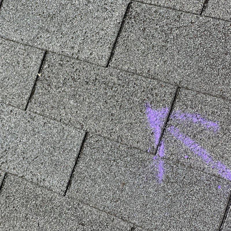 Roof shingles with storm damage marked for repair