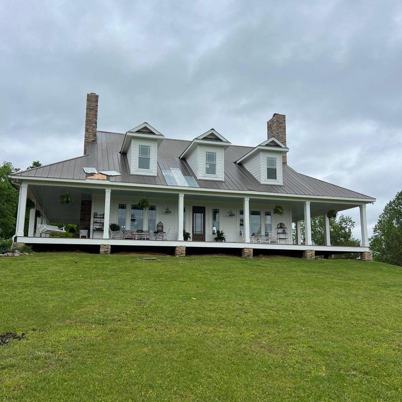 Metal roof with torn and loosened shingles on porch side