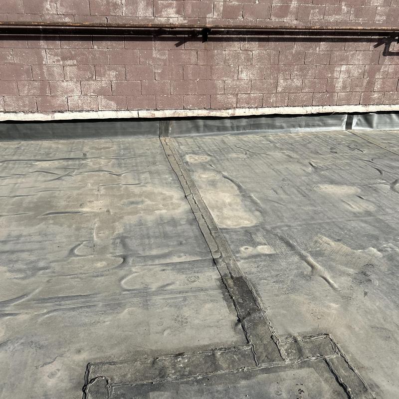 EPDM flat roof with sealed flashing repairs near wall