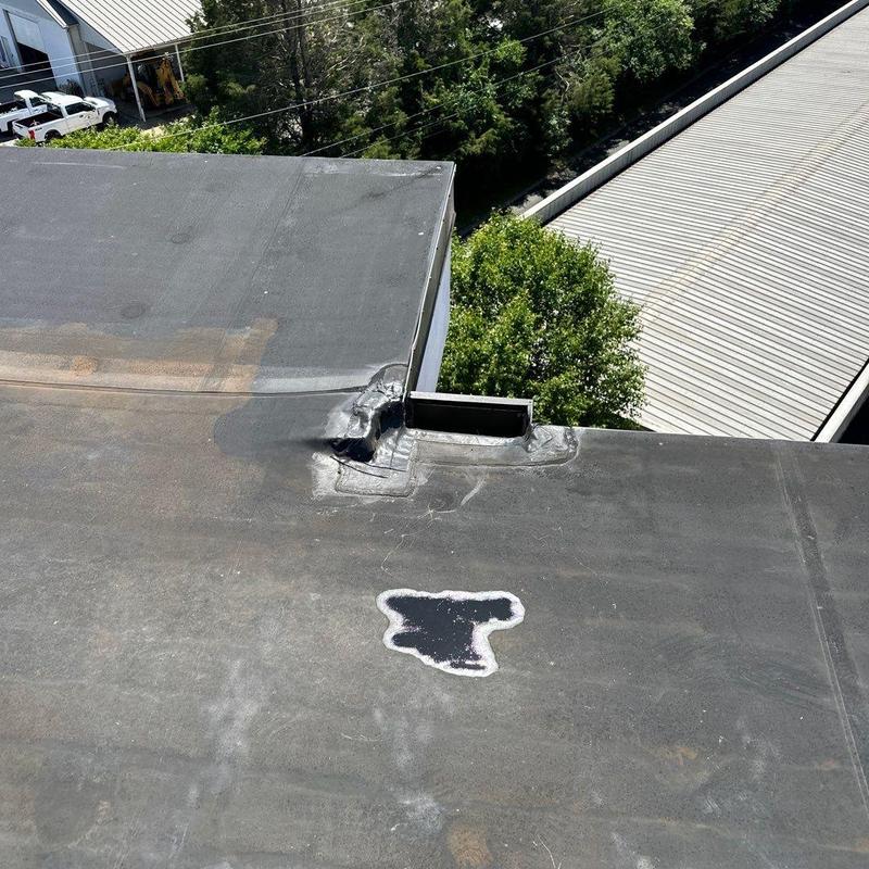 Flat commercial roof membrane with patched area near vent