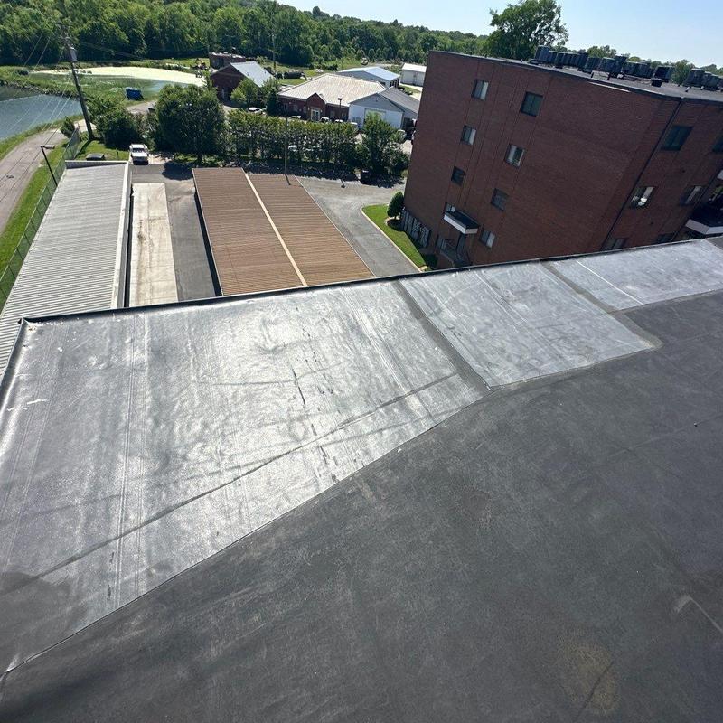 Flat roofing membrane with patch repairs on building rooftop