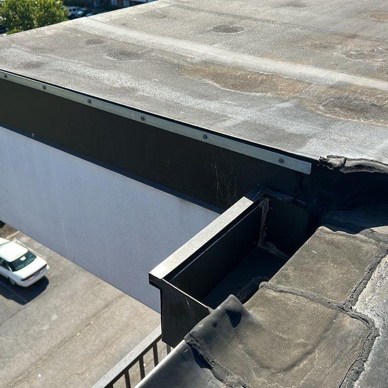 Roof edge metal flashing and damaged membrane near gutter