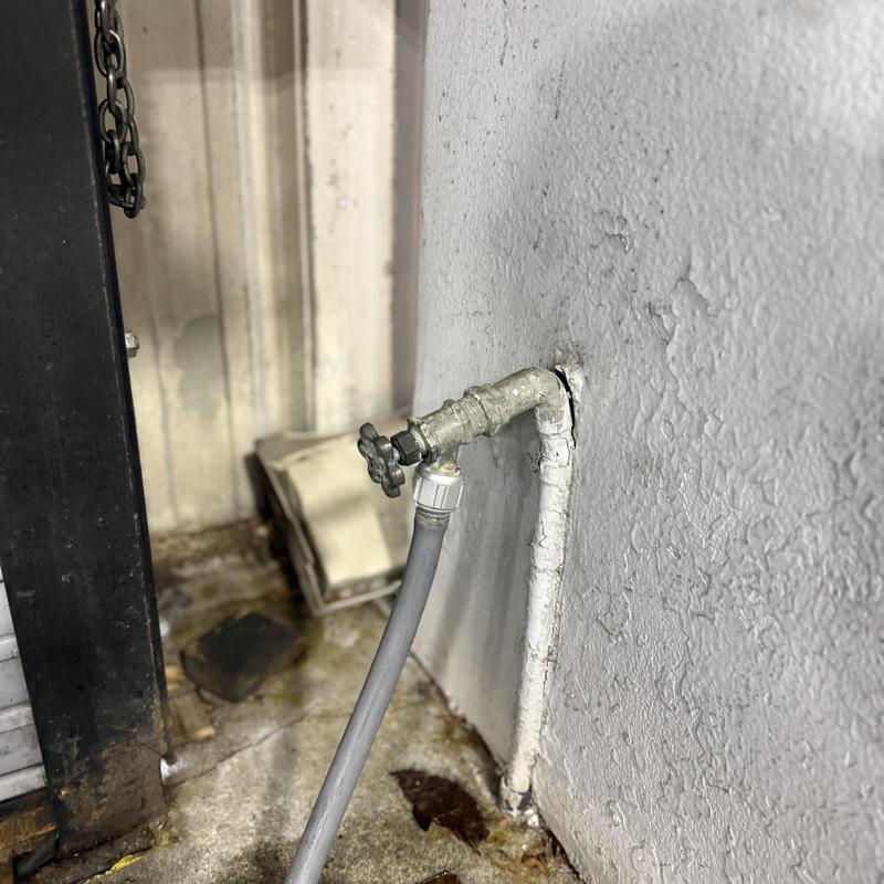 Hose bib with attached garden hose on exterior wall