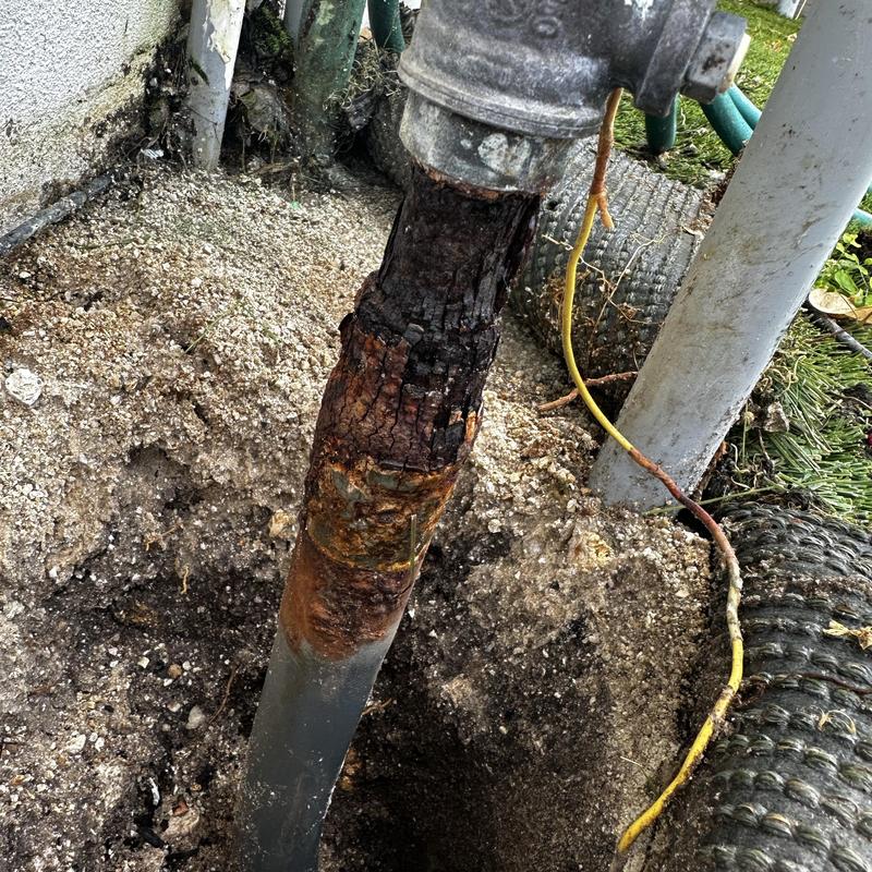 Corroded gas riser pipe exposed in dirt hole excavation