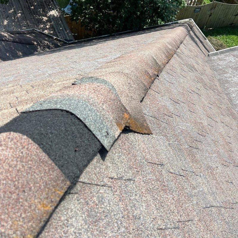 Damaged roof ridge shingles with visible wear and cracks