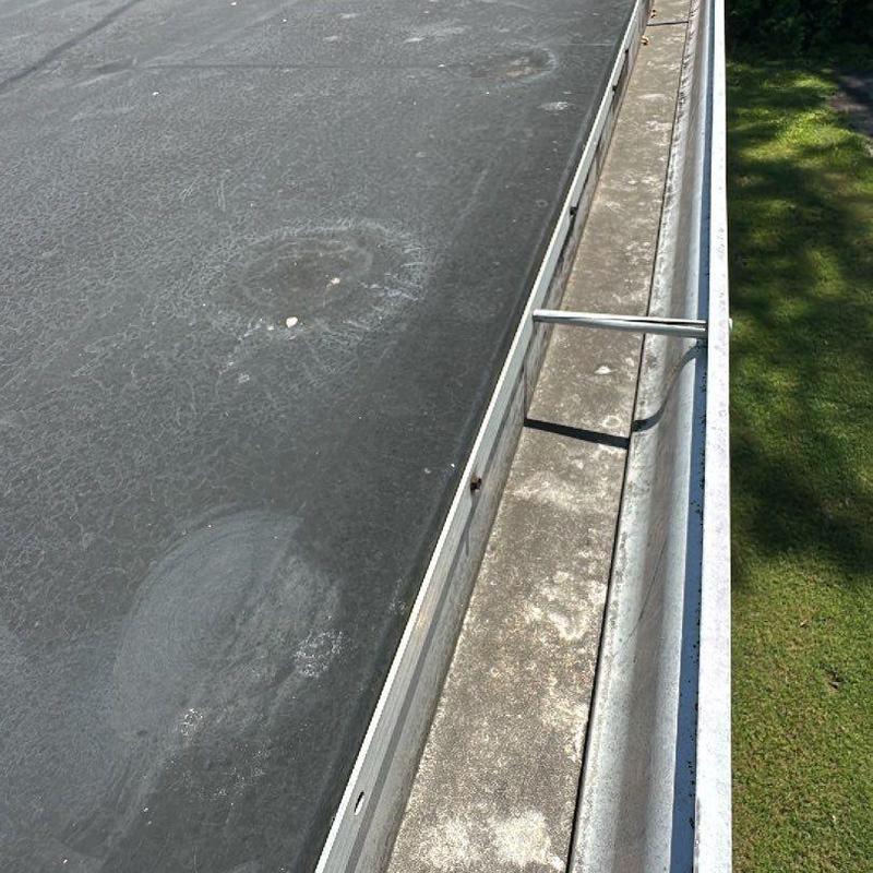 Flat roof membrane with wind damage near gutter line