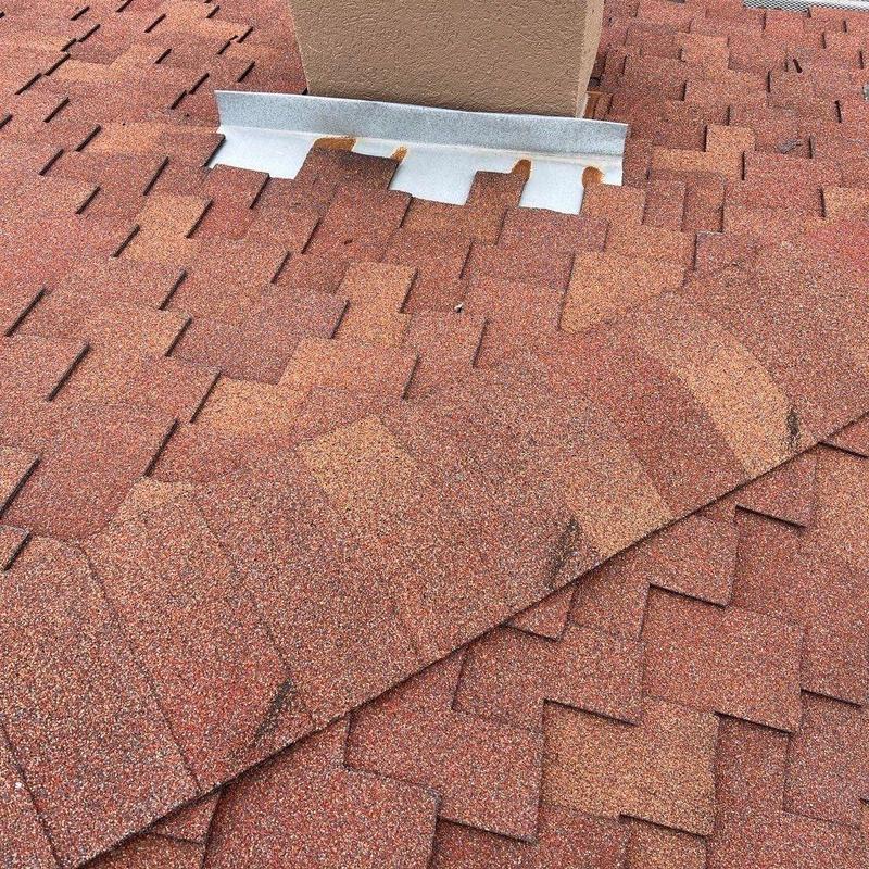 Asphalt shingles and chimney flashing with rust spots