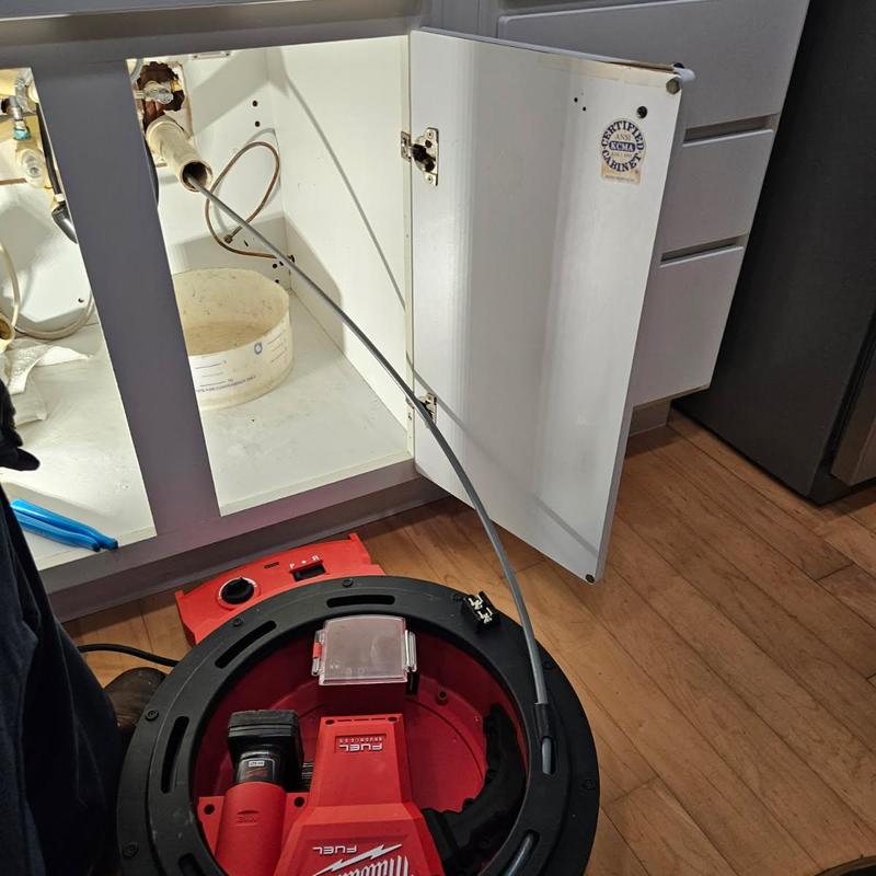 Kitchen drain line with clearing machine in use