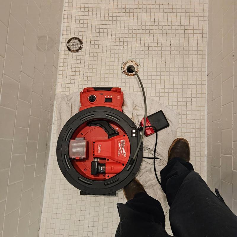 Shower drain with plumbing snake in tiled stall