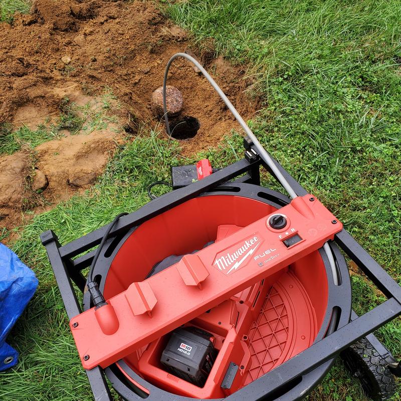 Main drain line snaking tool with hose in yard hole
