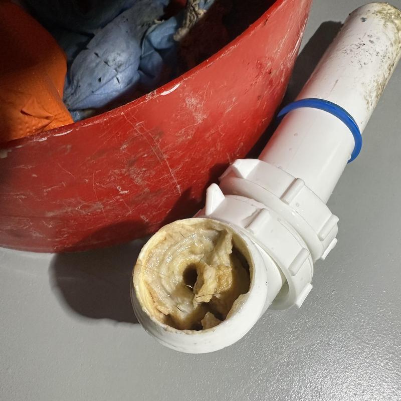 Sink drain pipe clogged with buildup debris removed