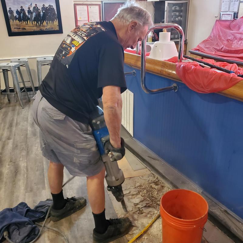 Concrete floor drilling with jackhammer near bar counter
