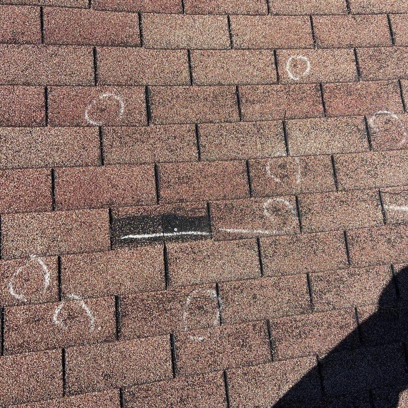 Asphalt shingle roof with storm damage marked for repair
