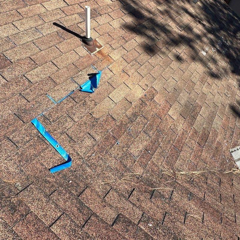 Storm-damaged asphalt shingles with blue tape markers