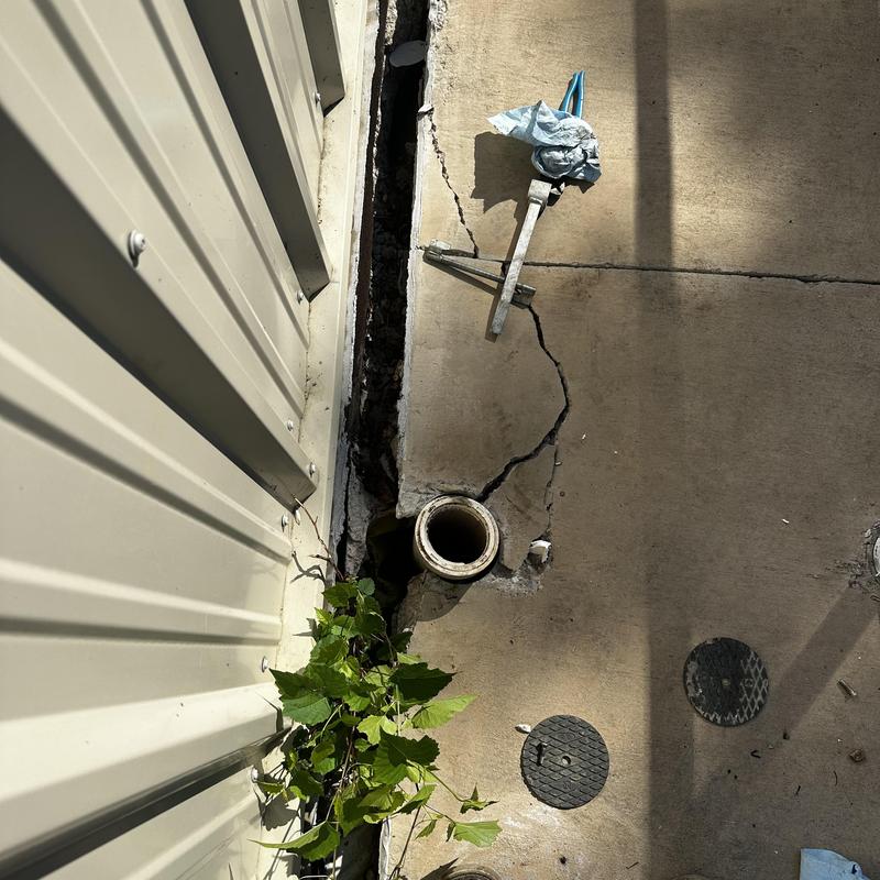 Broken exterior sewer cleanout with cracked concrete