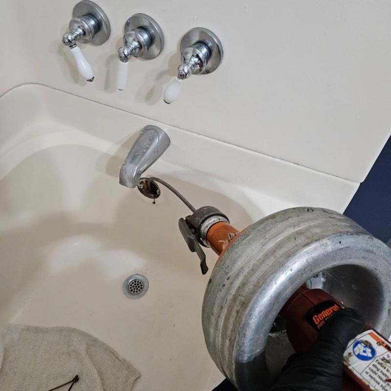 Tub drain with plumbing snake clearing blockage