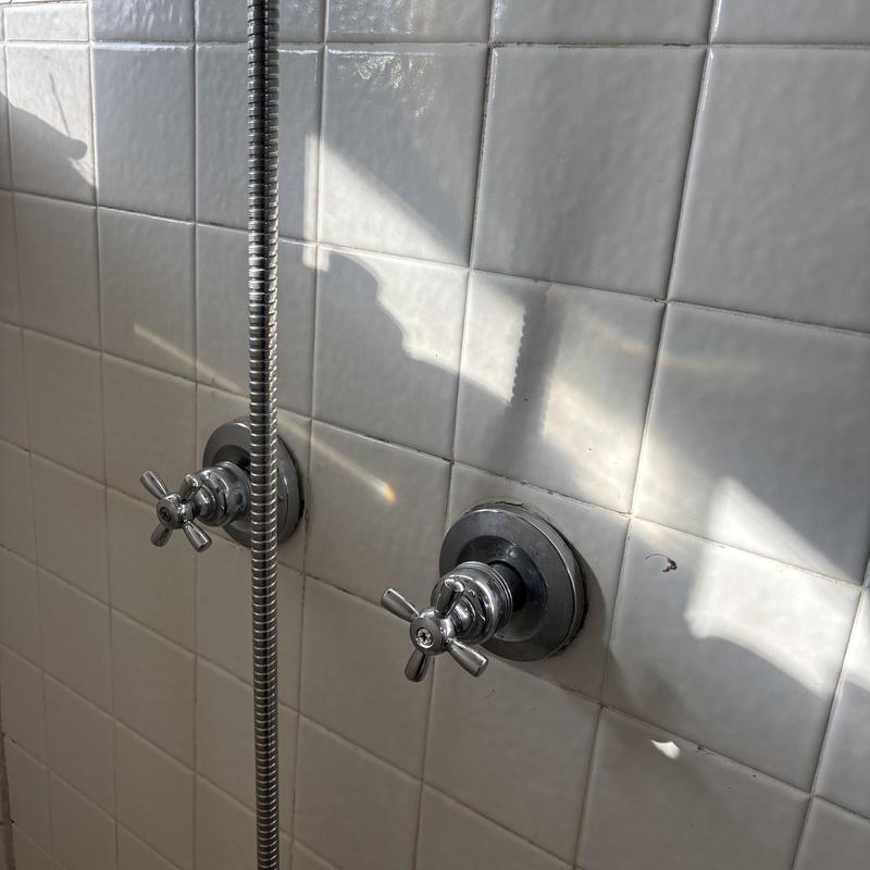 Shower stems and chrome handles on tiled wall