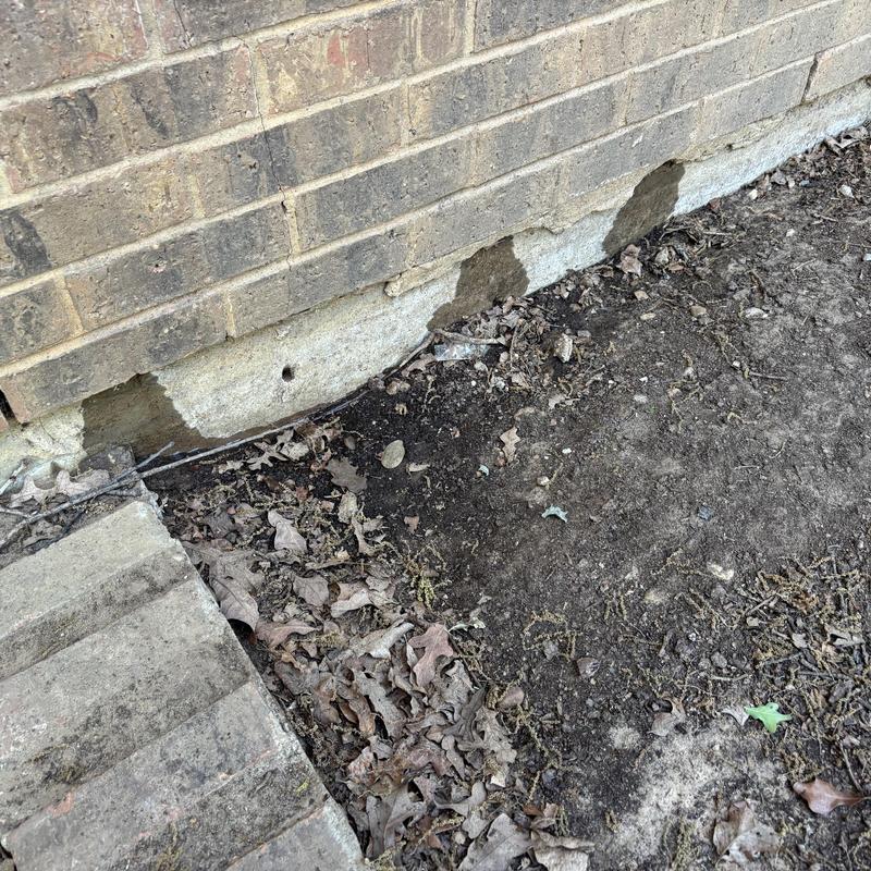 Brick foundation with soil erosion and damaged mortar