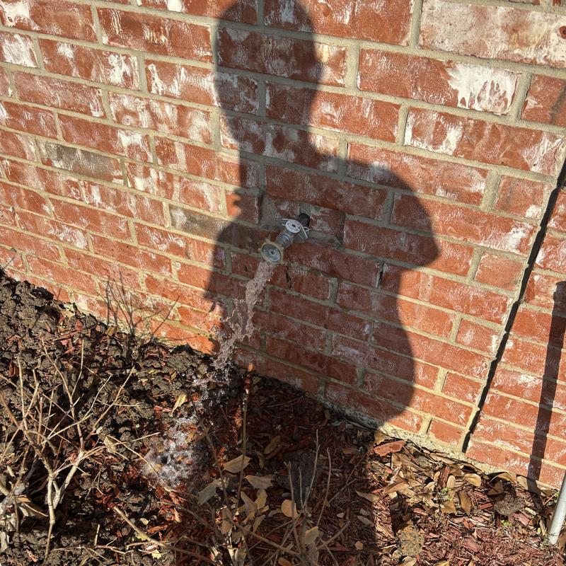 Outdoor water spigot with flowing water on brick wall