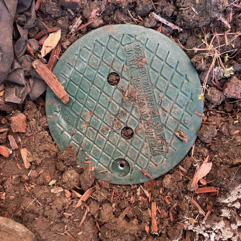 Irrigation control valve buried in soil with mulch