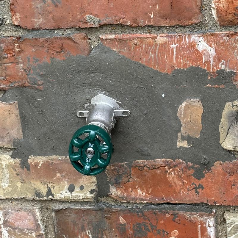 Frost proof hose bib with fresh mortar patch on brick wall