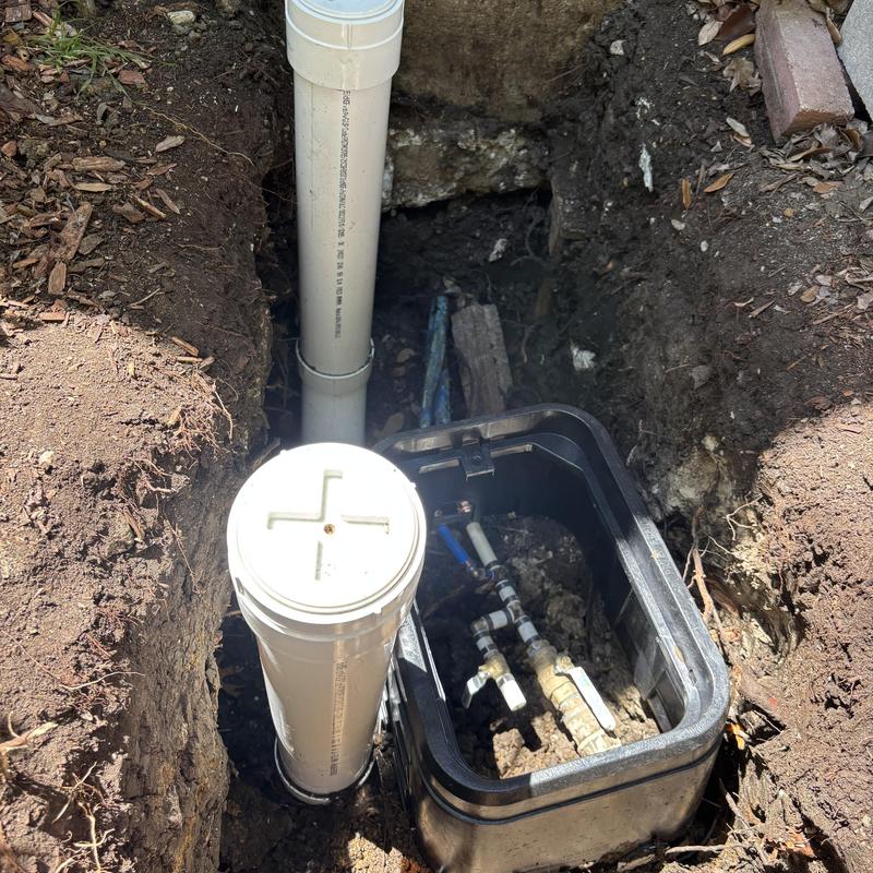 PVC irrigation valve box with plumbing manifold in soil trench