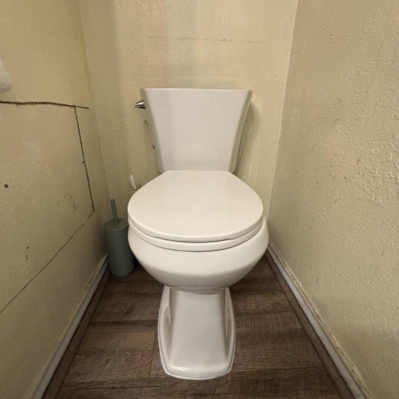 Toilet with replaced PVC flange in narrow bathroom nook