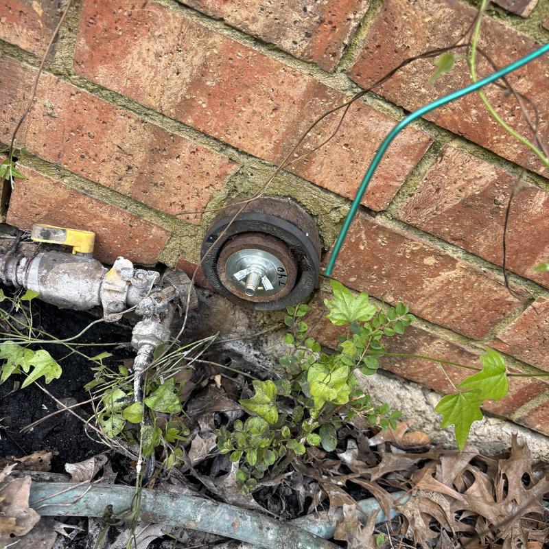 Water spigot with valve and grounding wire by brick wall