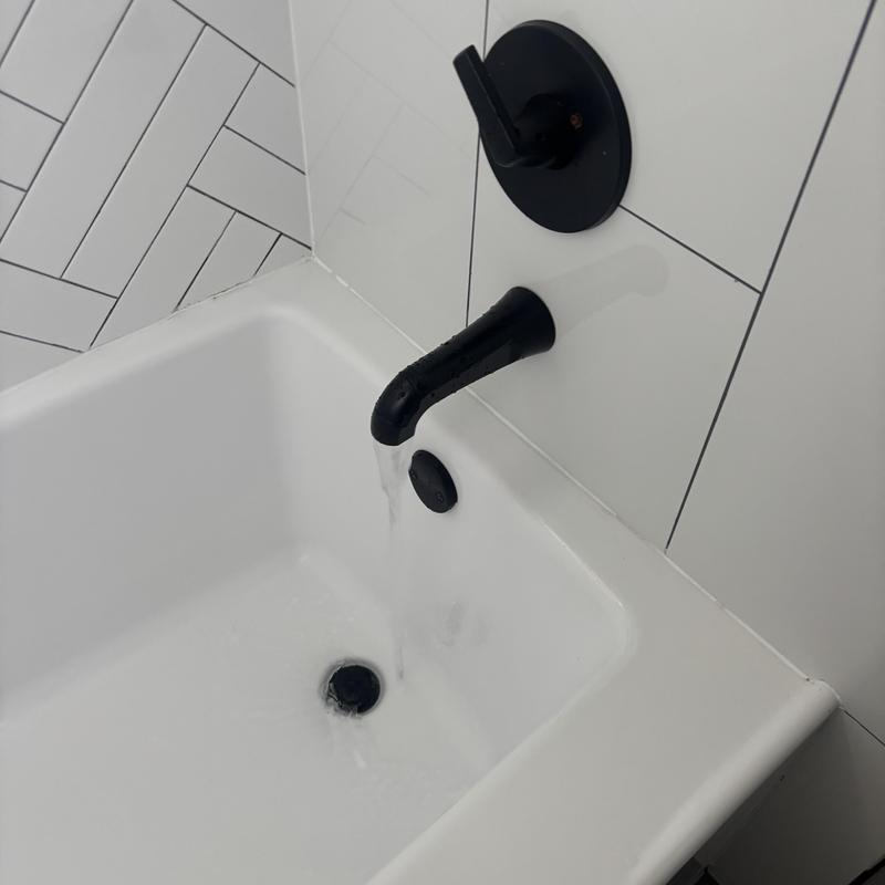 Bathtub faucet with black handle and water flow