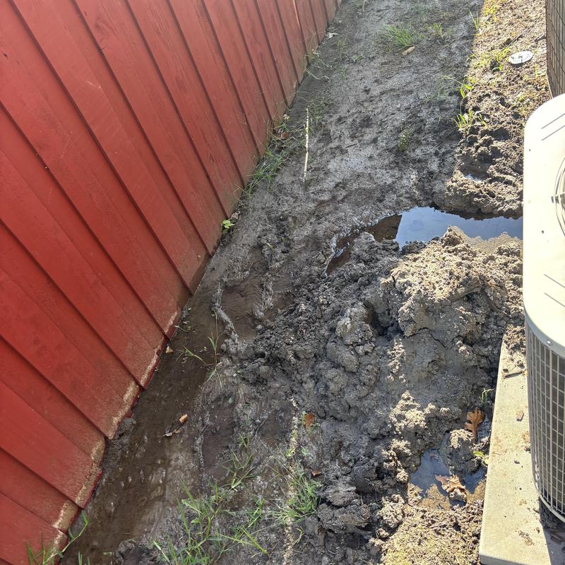 Slab leak area with muddy ground near fence and unit