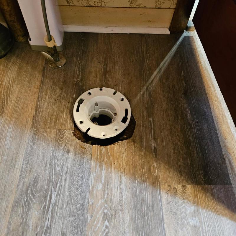 Toilet flange installed in wood floor cutout