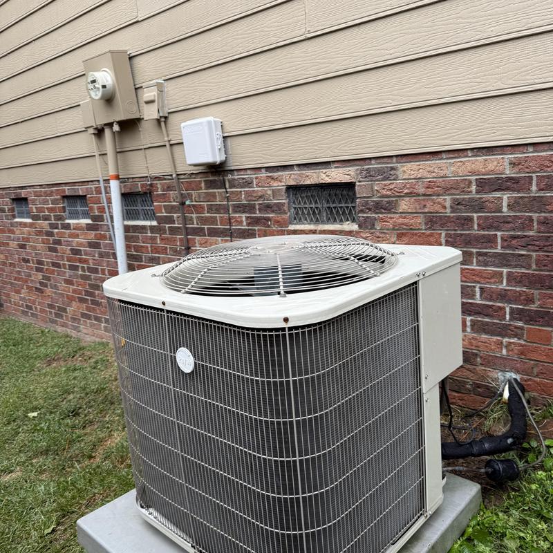 Outdoor air conditioning condenser unit on house exterior