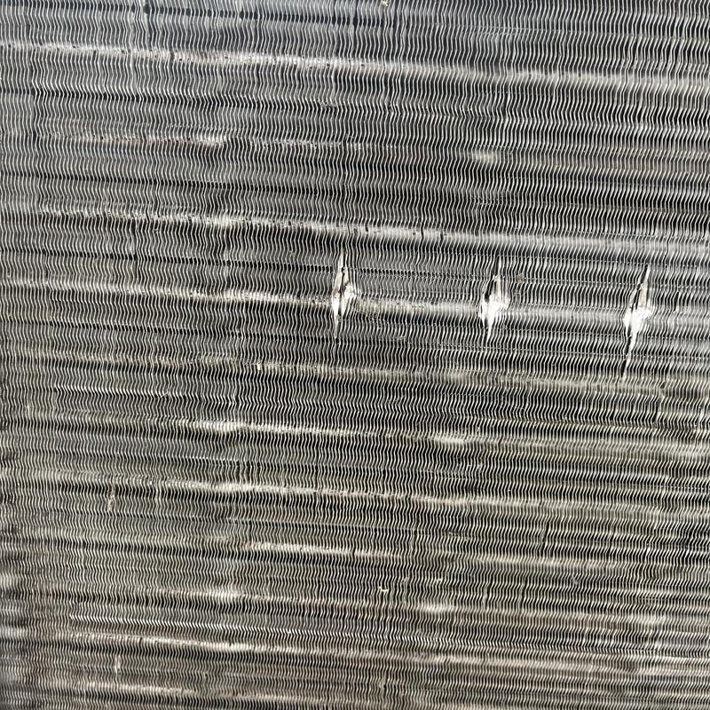 Air conditioner condenser coil with visible damage and dirt