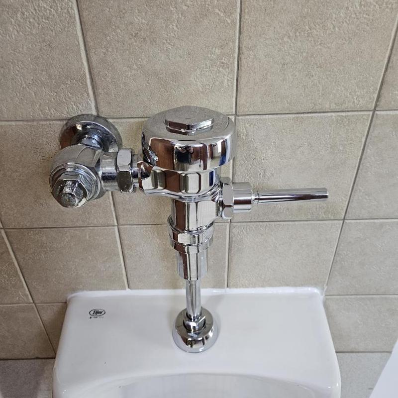 Urinal flush valve installation on tiled wall