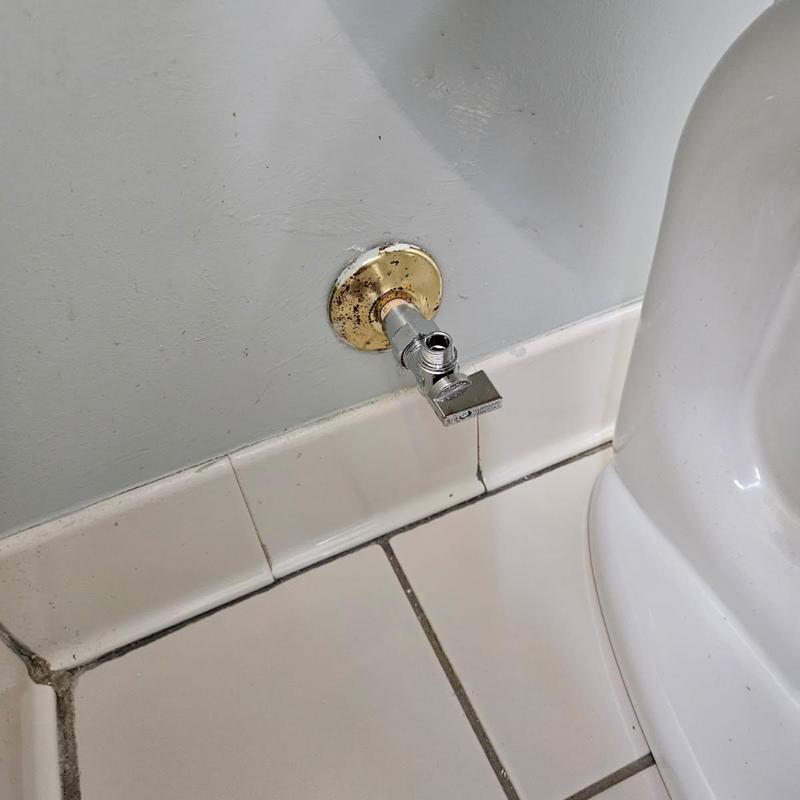 Angle valve installation next to toilet on tiled floor