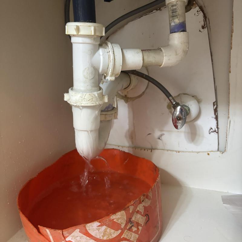Bathroom sink drain pipe draining into bucket